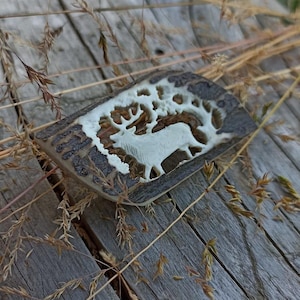 Um broche de chifre esculpido à mão com um motivo de veado/alce