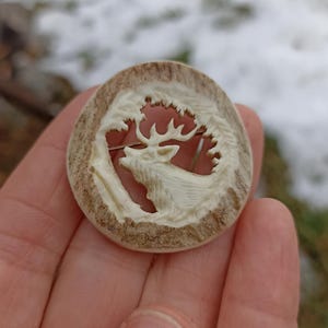 Um broche de chifre esculpido à mão com um motivo de veado/alce