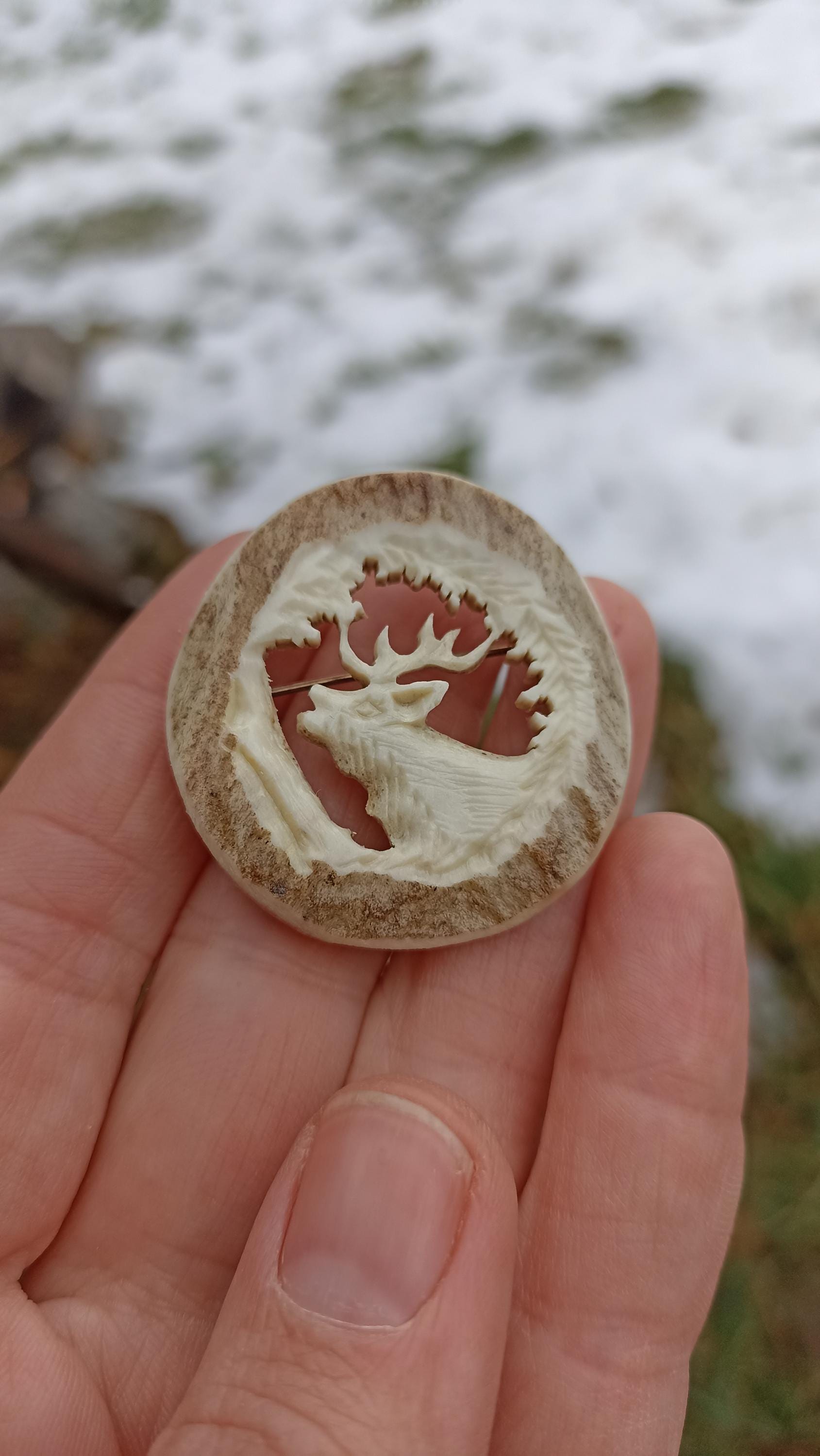 A hand-carved antler brooch with a motif of a deer/elk