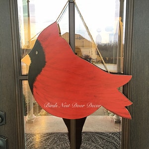May include: Red cardinal bird wooden door hanger with black accents and the text "Birds Nest Door Decor".