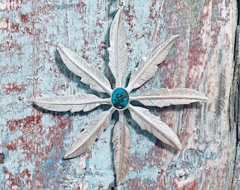 Handmade silver and turquoise pendant necklace formed by a star of 8 silver feathers surrounding a turquoise centre