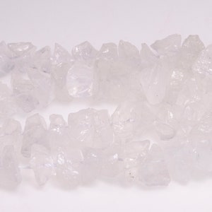 May include: A strand of small, irregular, clear, and translucent quartz crystal chips. The chips are clustered together and have a slightly pink hue.