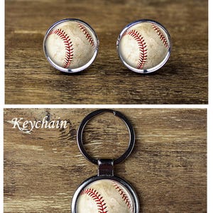 May include: Baseball-themed cufflinks and keychain. The cufflinks feature a baseball design with red stitching and a silver border. The keychain has a similar baseball design with a silver keyring.