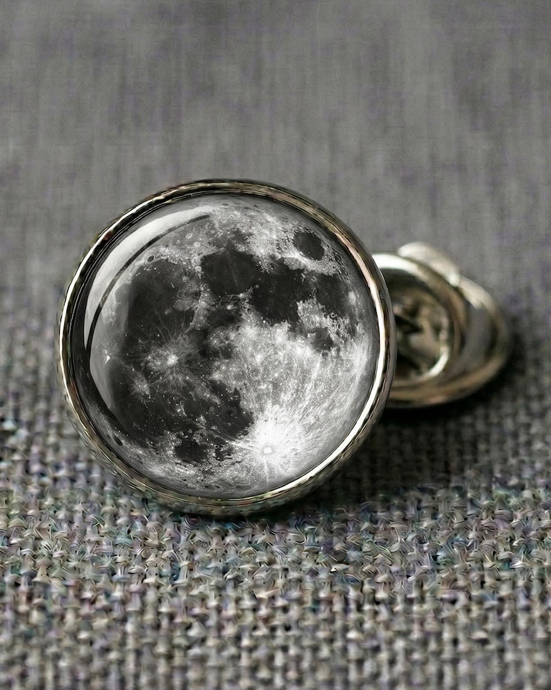 Full moon lapel pin silver tone brass with photorealistic moon surface craters epoxy dome, displayed on grey fabric, astronomy space celestial gift.