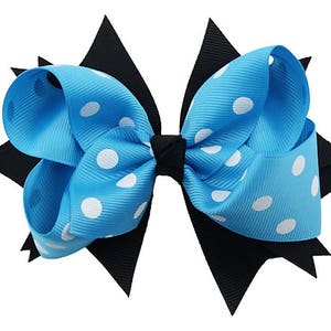 May include: A blue and black hair bow with white polka dots. The bow is made of ribbon and has a layered design.