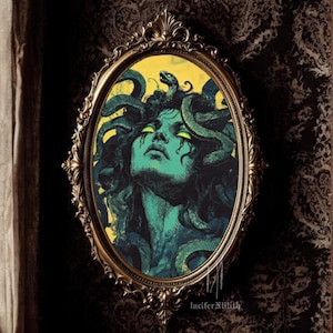 May include: A vintage-style oval mirror with a gold frame, featuring a painting of Medusa, a mythical Greek figure with snakes for hair, against a yellow background. The text "luciferxlilith" is visible at the bottom of the image.