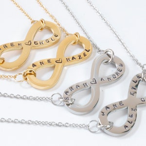 May include: Three infinity symbol necklaces with personalized names and a heart symbol. The top necklace is gold with the names "Karen" and "Chloe". The middle necklace is gold with the names "Jane" and "Hazel". The bottom necklace is silver with the names "Sarah", "Andrew", "Jane", "Kyle", and "Alex".