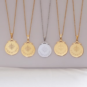 Puede incluir: Cinco collares de oro y plata con colgantes de brújula. Cada colgante tiene una rosa de los vientos y coordenadas grabadas. Las coordenadas son 51° 30' 26" N 7° 39.9" W, 40° 40' 41" N 73° 56' 36" W, 41° 29.5' N 28° 58' 30" E, 35° 37' 23" N 2° 21' 7.99" E y 35° 41' 22" N 139° 41' 30" E.