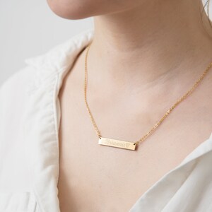 May include: A gold chain necklace with a bar pendant engraved with the name "Brionna" and a small heart symbol.