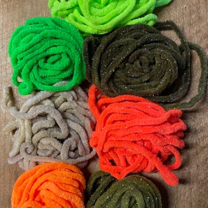 May include: Six spools of sparkly fly tying thread in various colors, including green, brown, tan, orange, and olive.