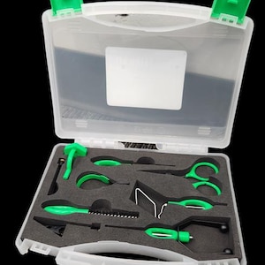 May include: A white plastic toolbox with a clear lid, open to reveal a set of tools with green accents. The tools are arranged in a foam insert, including scissors, pliers, and other specialized instruments. The toolbox is on a black background.