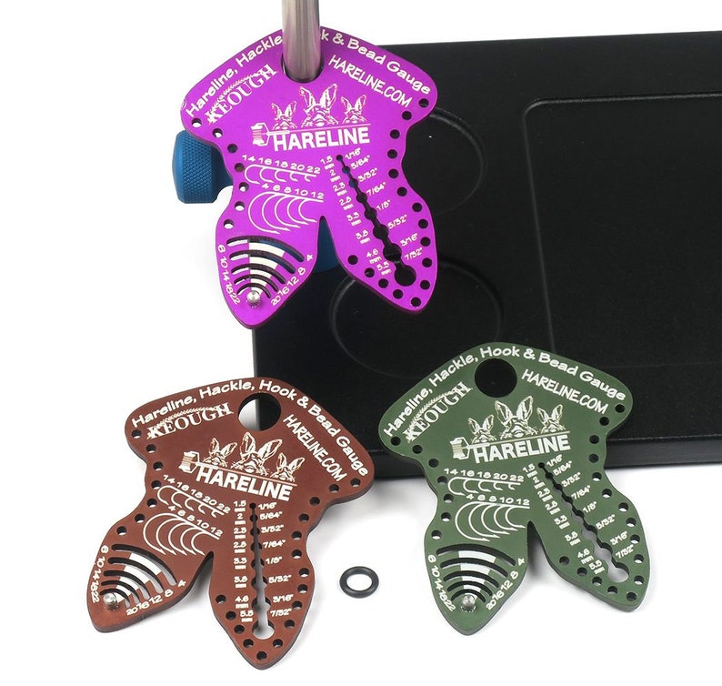Pode incluir: Tr&ecirc;s ferramentas de amarra&ccedil;&atilde;o de moscas de metal de diferentes cores, cada uma com a forma de um coelho com o texto "Hareline, Hackle, Hook & Bead Gauge" e "HARELINE.COM". As ferramentas t&ecirc;m marcas para medir os tamanhos dos ganchos, os tamanhos das contas e os tamanhos das penas.