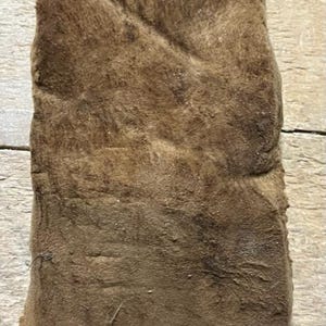 Könnte beinhalten: Ein Stück braunes Leder mit rauer Textur. Das Leder ist gefaltet und weist einen abgenutzten Look auf.