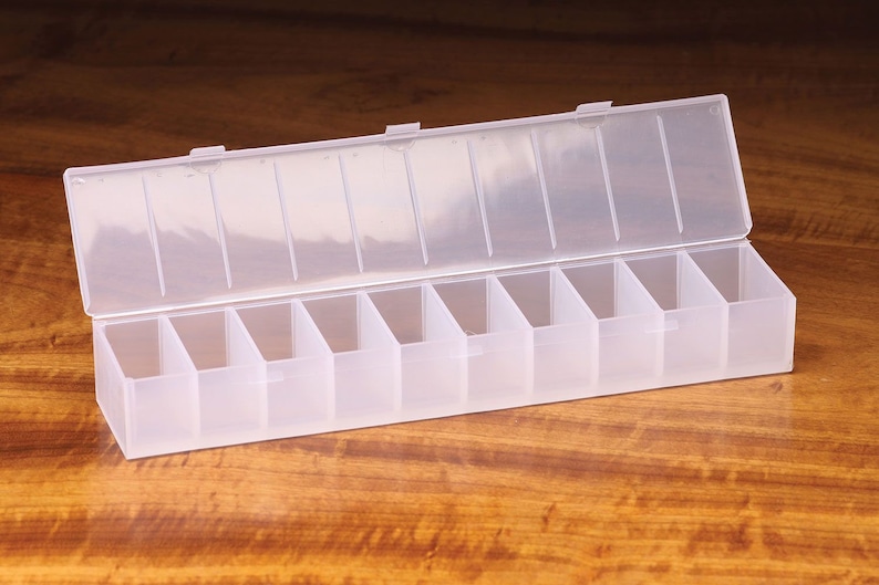 K&ouml;nnte beinhalten: Eine transparente Plastik-Aufbewahrungsbox mit 10 F&auml;chern. Die Box ist ge&ouml;ffnet und der Deckel liegt obenauf.