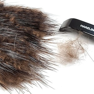 Könnte beinhalten: Nahaufnahme von Fliegenbindematerialien. Ein dunkelbrauner Fellklumpen liegt neben einem schwarzen Werkzeug mit dem Aufdruck "HARELINE". Ein Teil des Fells wurde vom Klumpen entfernt.