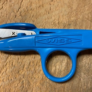 Peut inclure: Ciseaux à fils Wiss bleus avec une lame argentée et une poignée en anneau.