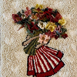 May include: A handmade rug featuring a whimsical design of a figure carrying a large bouquet of flowers. The figure's skirt is red and white striped, and the flowers are in shades of red, pink, and yellow. The background is a textured, off-white color.