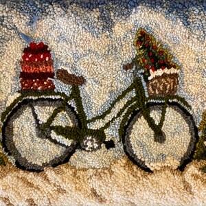 May include: A hand-tufted rug depicting a winter scene. A green bicycle carries a Christmas tree in a basket and a stack of gifts. The background shows snow and evergreen trees. The rug is made with various shades of green, brown, white, and blue.