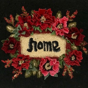 May include: A black rug with a floral design and the word "home" in the center. The flowers are red and pink, with green leaves. The word "home" is in black script.