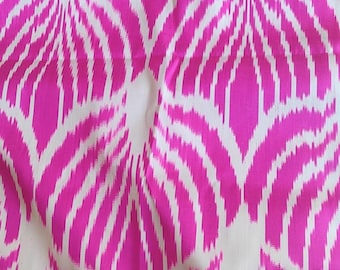 May include: Close-up of a fabric with a repeating pattern of pink and white abstract shapes. The design features curved lines and petal-like forms, creating a dynamic visual texture. The fabric appears to be a lightweight material.