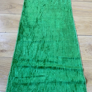 Puede incluir: Un trozo de tela de terciopelo verde con una superficie texturizada.