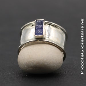 Può includere: Un anello d'argento con una fascia larga e una pietra preziosa rettangolare blu incastonata al centro.