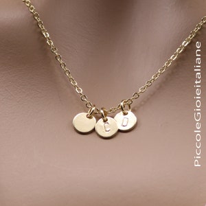 Può includere: Una collana a catena d'oro con tre piccoli dischi d'oro, ognuno con una lettera impressa. Le lettere sono C, O e D.