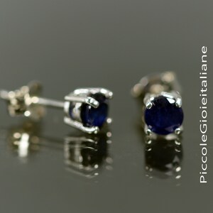 May include: A pair of silver stud earrings with dark blue round gemstones.