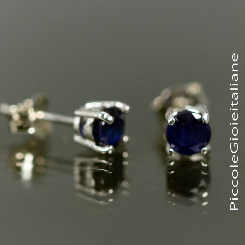 May include: A pair of silver stud earrings with dark blue round gemstones.