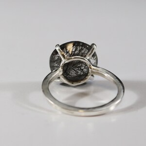 May include: A silver ring with a black and clear gemstone. The gemstone is a round cabochon with a silver setting.