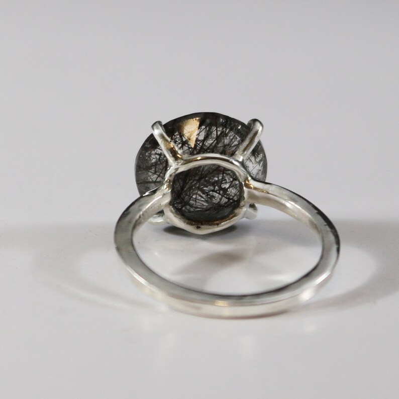 May include: A silver ring with a black and clear gemstone. The gemstone is a round cabochon with a silver setting.