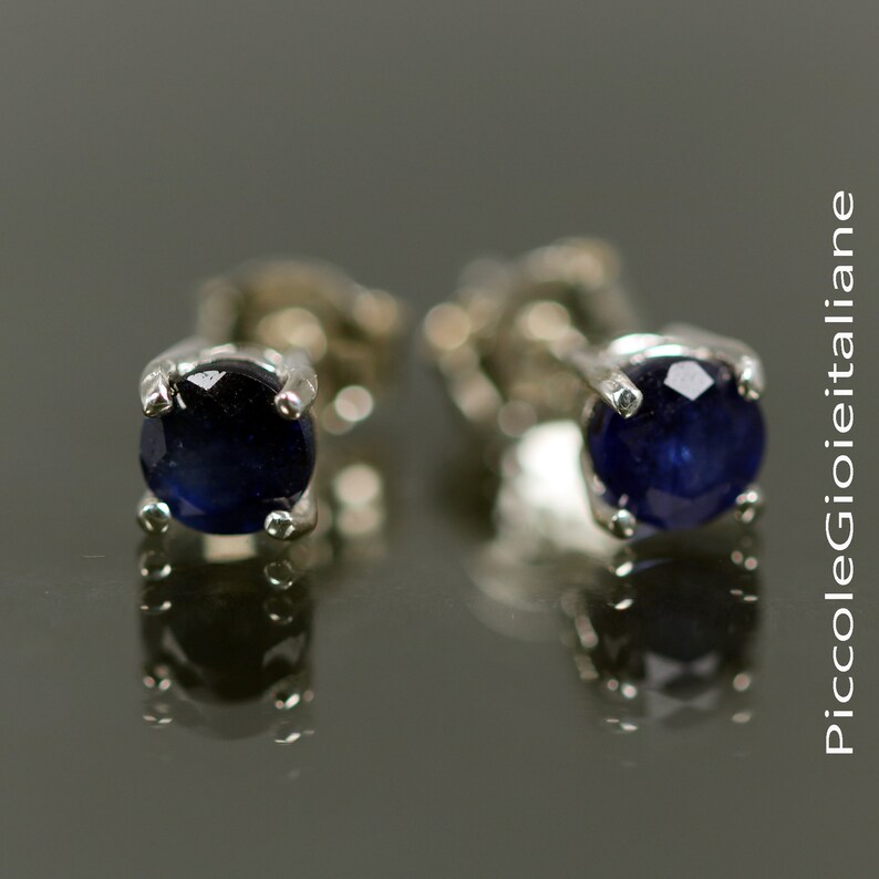 May include: A pair of silver stud earrings with round blue sapphire gemstones.