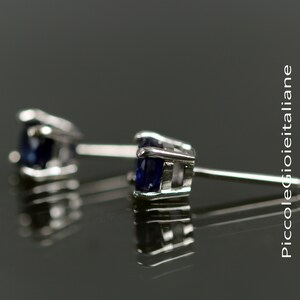 May include: A pair of silver stud earrings with a dark blue gemstone in each setting.