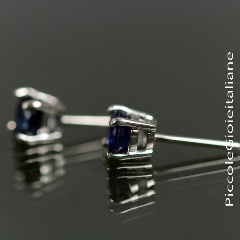 May include: A pair of silver stud earrings with a dark blue gemstone in each setting.