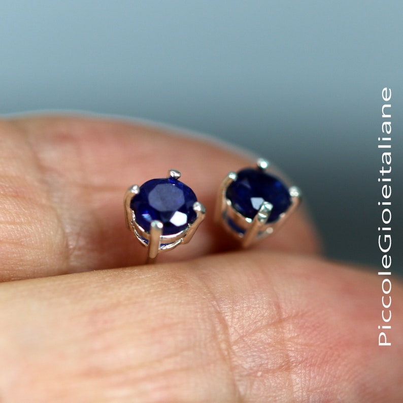 May include: A pair of silver stud earrings with round blue gemstones.