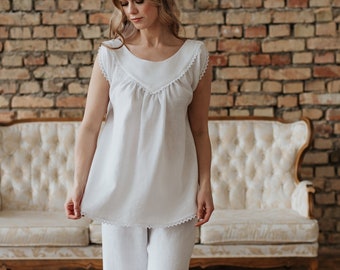 May include: A white cotton pajama set with lace trim. The top has a scoop neck and short sleeves. The pants are wide-legged and have a relaxed fit.