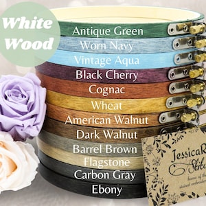 May include: A stack of wooden embroidery hoops in various colors, including Antique Green, Worn Navy, and Ebony. Each hoop has a metal clasp and screw. The image also features two roses and a business card that reads "JessicaRose Stitchery".