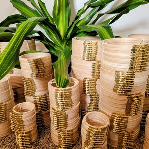 May include: A stack of wooden embroidery hoops with gold metal clasps. The hoops are stacked in various sizes and are arranged in a semi-circle.