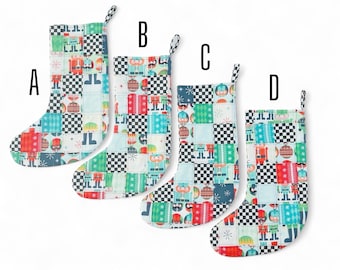 May include: Four Christmas stockings with a patchwork design. Each stocking features a mix of colorful squares with holiday-themed patterns, including toy soldiers and ornaments, and black and white checkered accents. The stockings are labeled A, B, C, and D.
