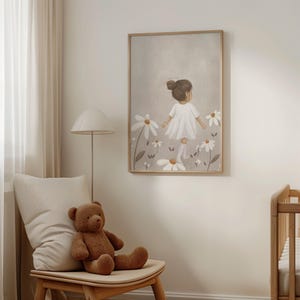 May include: A framed art print depicts a child in a white dress walking through a field of large daisies. The artwork has a neutral color palette with a light brown wooden frame. A brown teddy bear sits on a wooden chair.