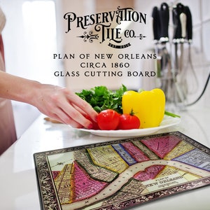 May include: A glass cutting board featuring a vintage map of New Orleans, circa 1860. The board is decorated with a black frame and the text "Preservation Tile Co."