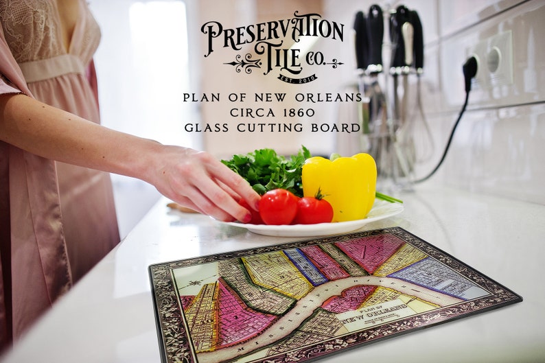 May include: A glass cutting board featuring a vintage map of New Orleans, circa 1860. The board is decorated with a black frame and the text "Preservation Tile Co."