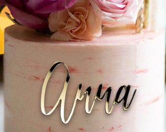 Può includere: Una torta rosa con un topper di glitter dorato e un topper con nome in acrilico dorato che dice "Anna".