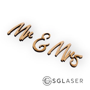 Op de afbeelding: Houten uitsnijding van de woorden "Mr. & Mrs." in een cursief lettertype. De uitsnijding is lichtbruin van kleur en bevindt zich op een witte achtergrond.