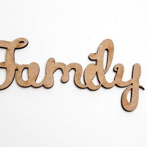 Może przedstawiać: Drewniany znak z napisem "Rodzina" napisanym kursywą.