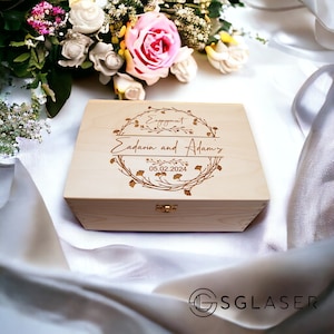 Könnte beinhalten: Eine Holzkiste mit einem gravierten Design. Das Design zeigt einen floralen Kranz mit den Worten "Engagement", "Eadaoin and Adam's" und "05.02.2024".
