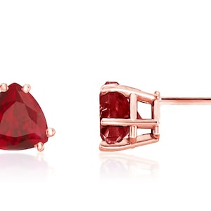 May include: A pair of rose gold earrings with a red triangular gemstone in each earring.