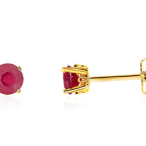 May include: A pair of gold stud earrings with a red ruby gemstone in each earring.