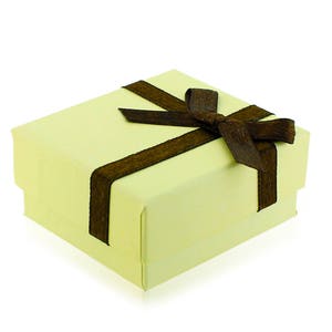 Op de afbeelding: Een kleine, lichtgele cadeaudoos met een bruin satijnen lint dat in een strik is gebonden.