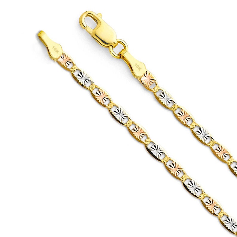 May include: A gold necklace with a delicate chain featuring alternating oval-shaped links. Each link has a starburst design with tri-color accents of yellow, rose, and white gold. The clasp is a lobster claw style. The necklace is marked "10K".